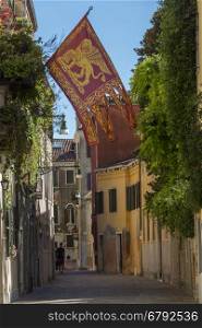 The flag of Venice in a quite street in Venice, Italy. The flag of the Italian region of Veneto historically used by the Republic of Venice from as early as 697AD.
