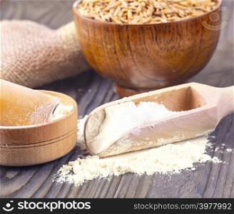 The flour pile and wheat grains in wooden spoon and bowl on wooden