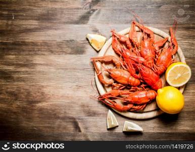 The food delicacies. Boiled crawfish with slices of lemon. On Wooden background.. The food delicacies. Boiled crawfish with slices of lemon.
