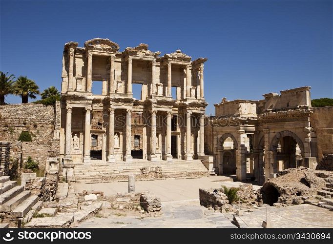 The front facade and courtyard of the library building at Ephesus is an imposing ancient Greek and Roman structure. Built from old stone and reconstructed by archaeologists, it is a popular tourist stop near the city of Izmir in Turkey.