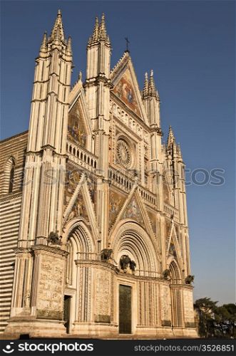 The front facade of the Orvieto Cathedral is ornate and detailed with colorful mosaics, intricate carvings, bronze statues, bell towers and more. It is a magnificent example of 14th century Italian architecture that evolved from Romanesque to Gothic.
