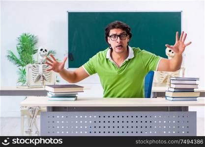 The funny male student in the classroom with skeleton. Funny male student in the classroom with skeleton