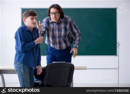The funny male teacher and boy in the classroom . Funny male teacher and boy in the classroom