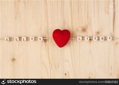 The german words for all love and a heart on a cord on wood