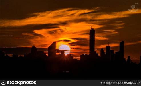 The giant beautiful sun setting behind the sky scrapers of New York City