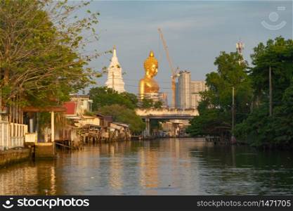 The Giant Golden Buddha in Wat Paknam Phasi Charoen Temple in Phasi Charoen district with boat on Chao Phraya River, Bangkok urban city, Thailand.
