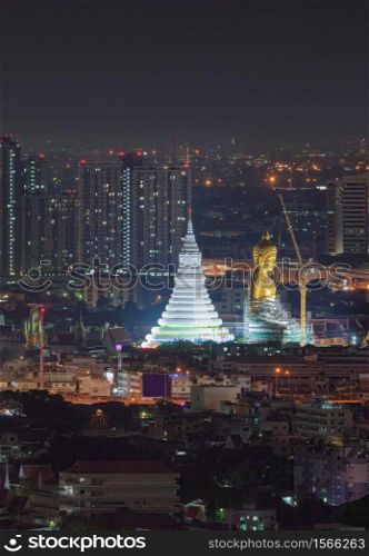 The Giant Golden Buddha in Wat Paknam Phasi Charoen Temple in Phasi Charoen district at night, Bangkok. Urban town, Thailand. Downtown City.