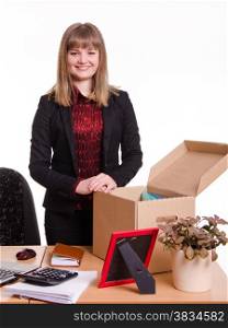 The girl accepted a job at the office and arranges personal belongings at the new workplace. Girl standing behind an office desk with a big box