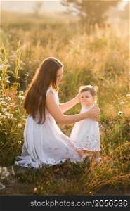 The girl and her mother bask in the spring sunshine.. Mother and daughter in sunny photos play among dandelions 3020.