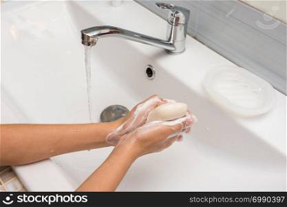 The girl carefully soaps her hands with soap, close-up