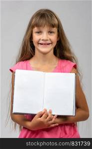 The girl cheerfully shows the opened empty book in her hands