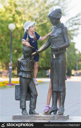 The girl climbed on the monument to the first teacher. Girl climbs first teacher sculpture located in the Krasnoarmeysk district of Volgograd Boulevard Engels
