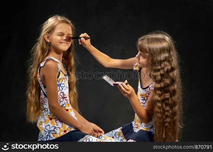 The girl closed her eyes when another girl powder her nose with a brush