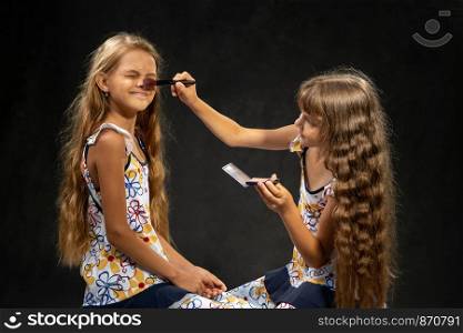 The girl closed her eyes when another girl powder her nose with a brush