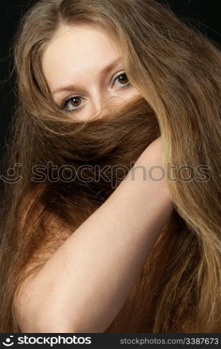 The girl closes long hair the bottom part of the person. A yashmak. On a black background