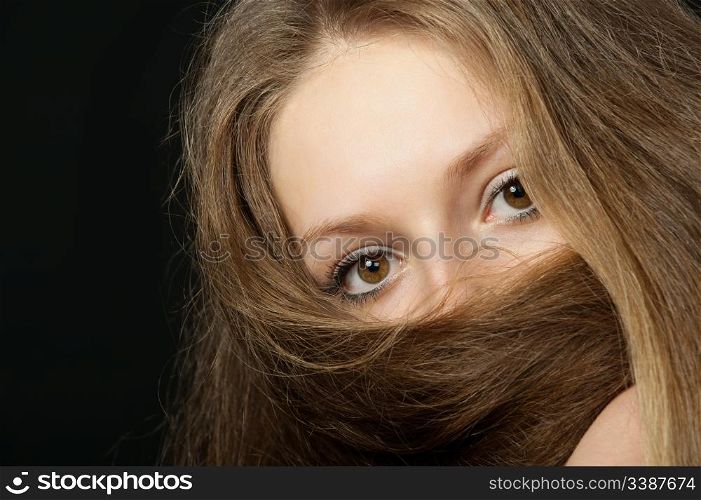 The girl closes long hair the bottom part of the person. A yashmak. On a black background