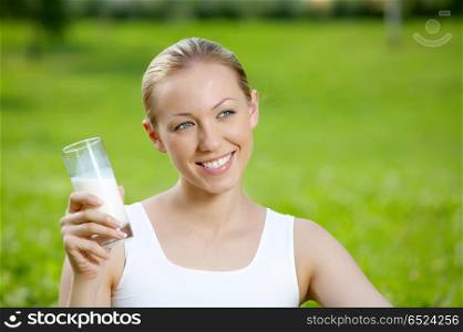The girl drinks milk against a summer landscape. Milk on the nature