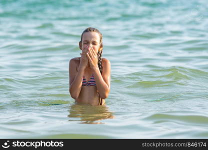 The girl drowned in sea water and wipes her nose and face with her hands