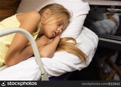 The girl fell fast asleep on the top shelf of a reserved seat car