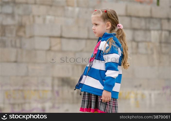 The girl four years walking on the embankment. Girl in a sweater looking to the left