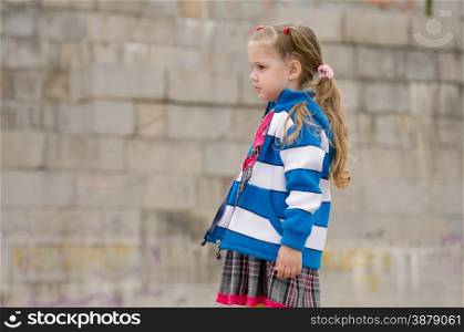 The girl four years walking on the embankment. Girl in a sweater looking to the left