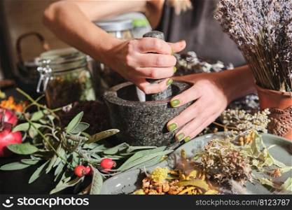 The girl grinds dry herbs in a mortar. Preparation of a mixture of dried herbs for making tea, medicines, tinctures. Phytotherapy, alternative medicine. 