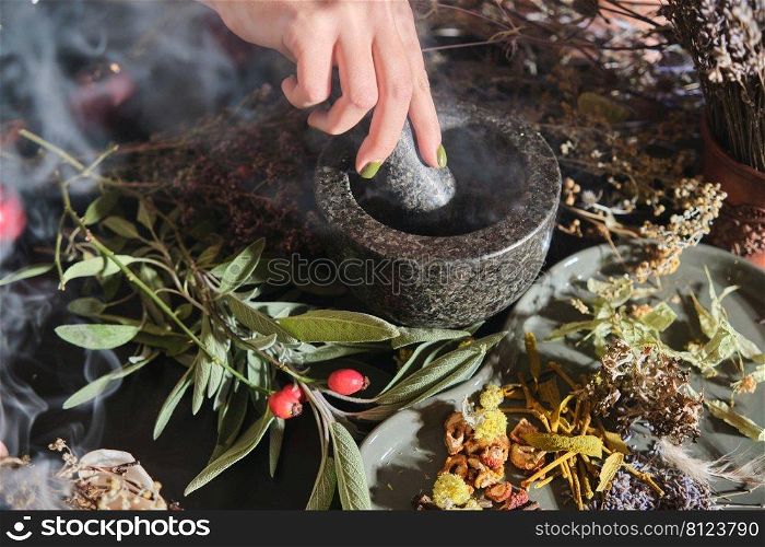 The girl grinds dry herbs in a mortar. Preparation of a mixture of dried herbs for making tea, medicines, tinctures. Phytotherapy, alternative medicine. 