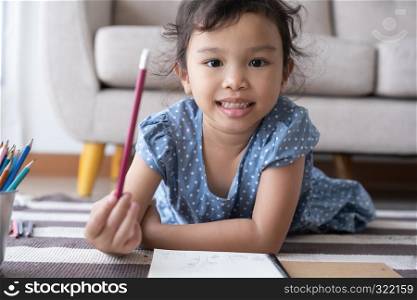The girl holding a pencil and smiling, aisan girl are drawing and happily at home