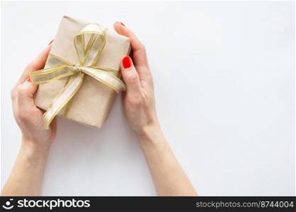 The girl holds a gift with a golden ribbon in her hands on a white background. Time to wrap presents. The concept of surprise, surprise loved ones. The girl holds a gift with a golden ribbon in her hands on a white background. Time to wrap presents. The concept of surprise, surprise loved ones.