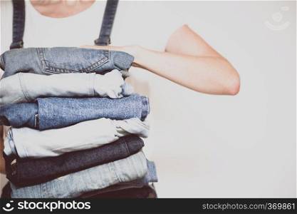 The girl holds a stack of jeans in her hands. cleaning in the closet. 