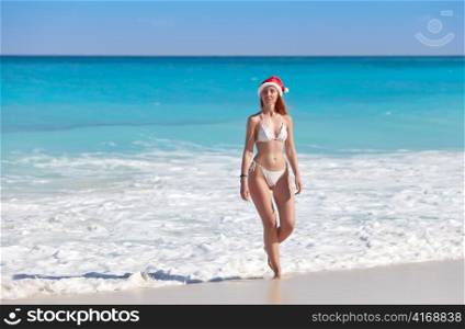 The girl in a hat of Santa Claus leaves the sea