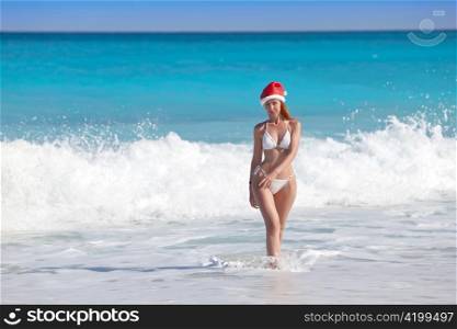 The girl in a hat of Santa Claus leaves the sea