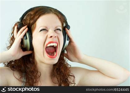 The girl in headphones shouts on a white background. Pleasure of a sound