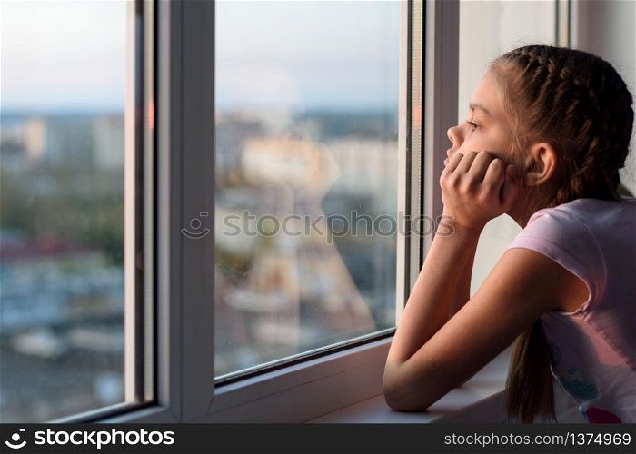 The girl in self-isolation looks out the window