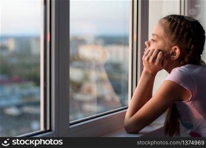 The girl in self-isolation looks out the window