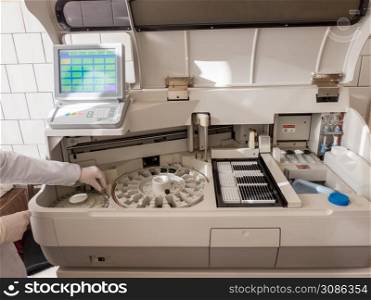 the girl in the lab puts the serum samples in a medical device for analysis. Machine automatic biochemical analysis. Indoors. . equipment medical laboratories