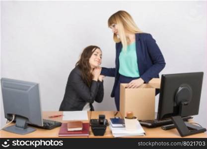 The girl in the office is facing the box with things and says goodbye to a colleague