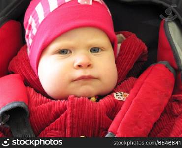 the girl in the red hat. girl in a red hat sitting in a stroller wearing seat belts