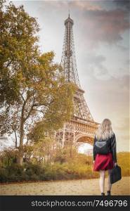 The girl in the red skirt goes against the background of the Eiffel Tower. Paris.