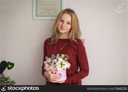 The girl in the room holding a vase with fresh flowers.. Beautiful and modest girl with a vase of flowers in his hands 9052.