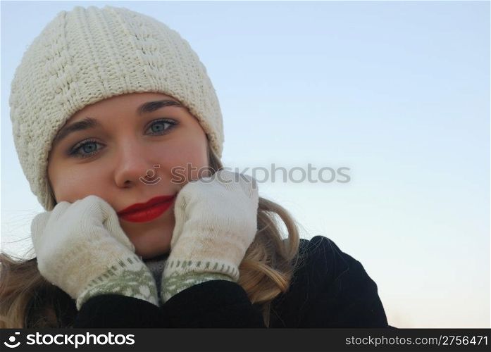 The girl in winter clothes. On a background of the blue sky