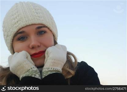 The girl in winter clothes. On a background of the blue sky