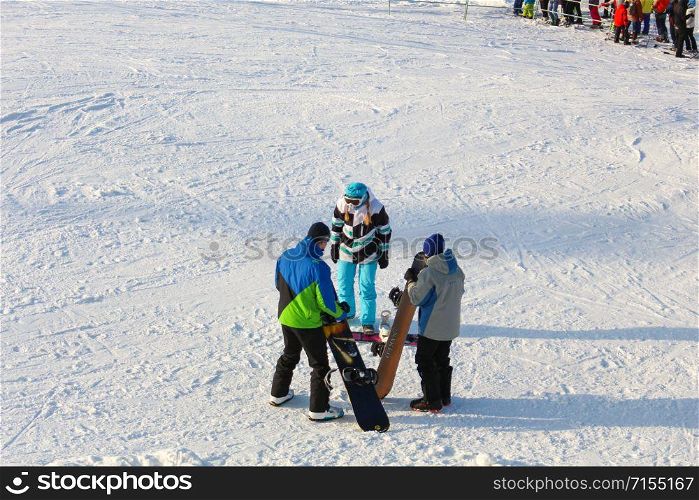 The girl instructor trains a teenager and a man snowboarding.. Khabarovsk, Russia - Dec 04, 2016: The girl instructor trains a teenager and a man snowboarding.