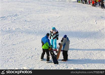 The girl instructor trains a teenager and a man snowboarding.. Khabarovsk, Russia - Dec 04, 2016: The girl instructor trains a teenager and a man snowboarding.
