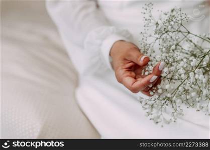 The girl is holding a bouquet of gypsophiles in her hands.. A small bouquet of gypsophila in female hands 3773.