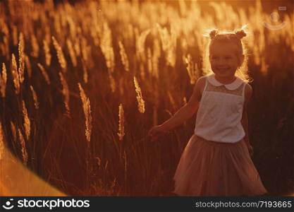 The girl is playing in the field among the herbs. beautiful girl at sunset. beautiful girl at sunset. The girl is playing in the field among the herbs