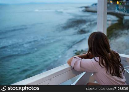 The girl is sitting in a cafe and looking at the sea, a beautiful evening.. The girl is sitting in a cafe and looking at the sea, a beautiful evening