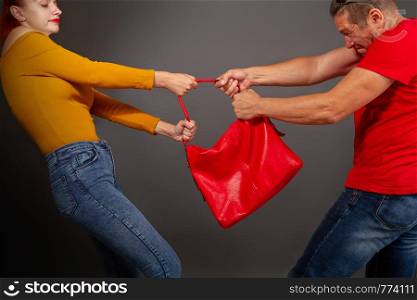 the girl is trying to prevent the robber who wants to pull the bag out of her hands. robber takes bag