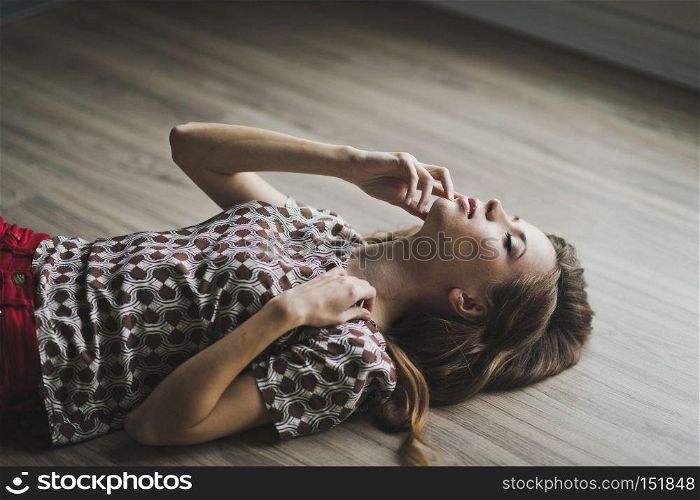 The girl lay on the parquet floor, arms outstretched.. Portrait of a girl with flowing hair lying on the floor 6967.