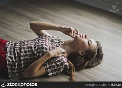 The girl lay on the parquet floor, arms outstretched.. Portrait of a girl with flowing hair lying on the floor 6967.